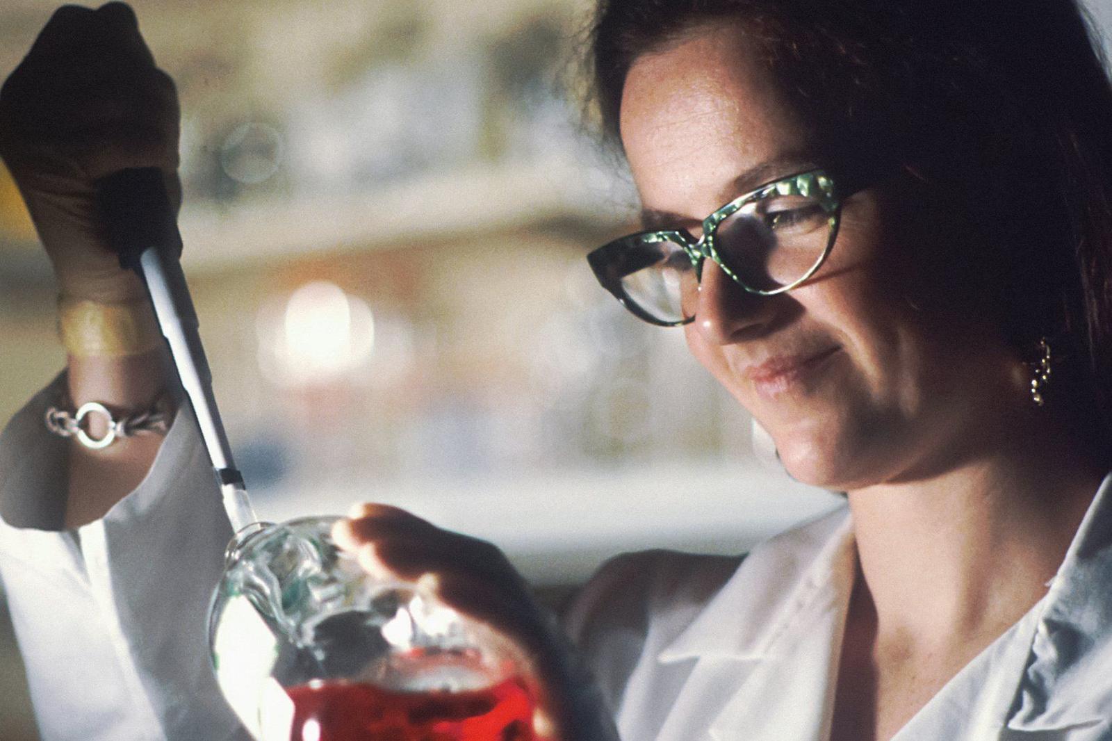 Pesquisadora analisando solução em frasco no laboratório