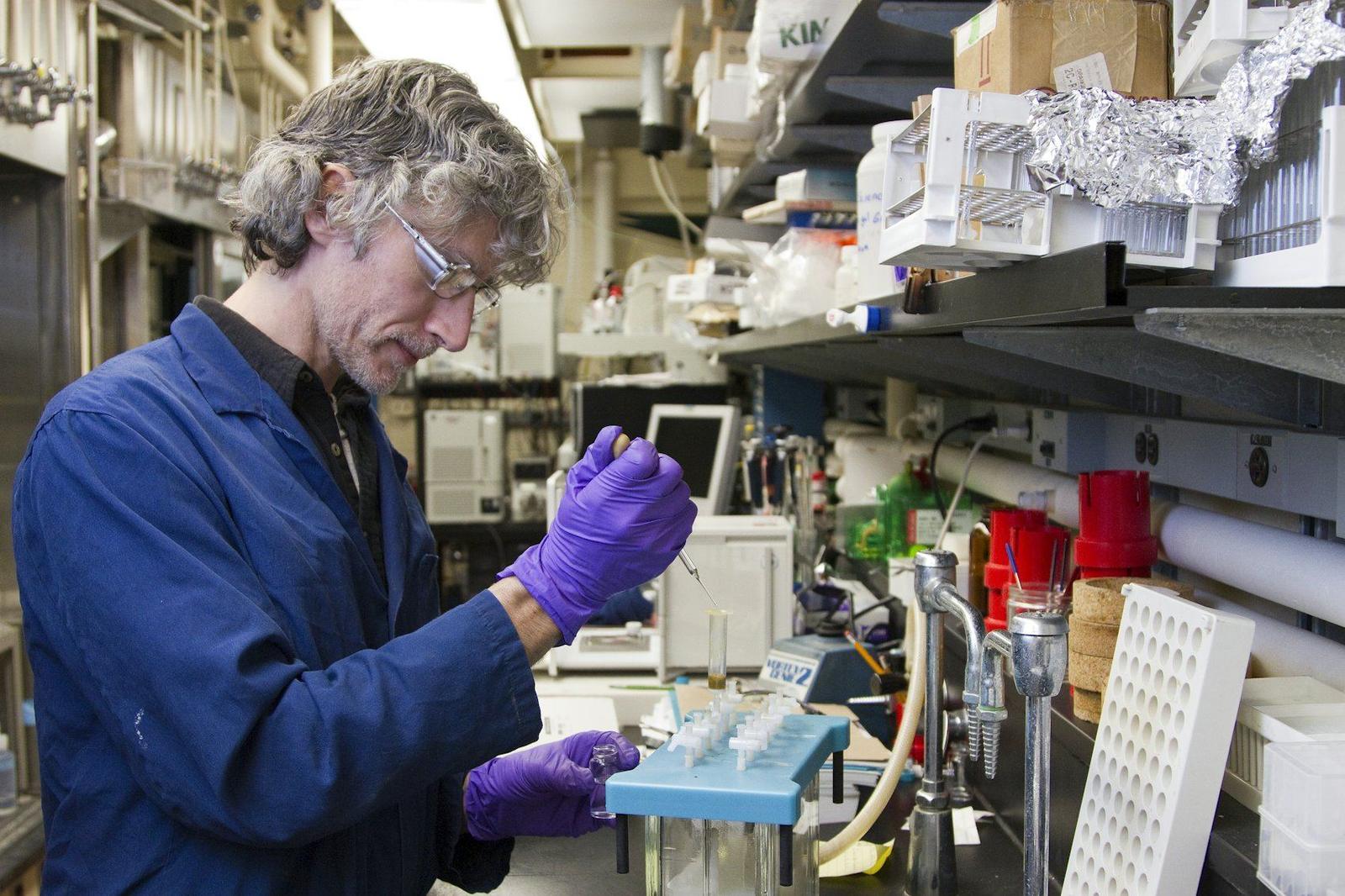 Pesquisador pipetando amostras em bancada de laboratório